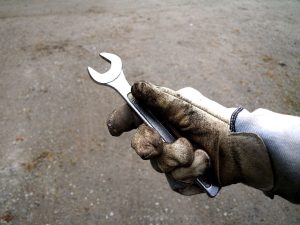 gloved hand of a maintenance technician holding a wrench