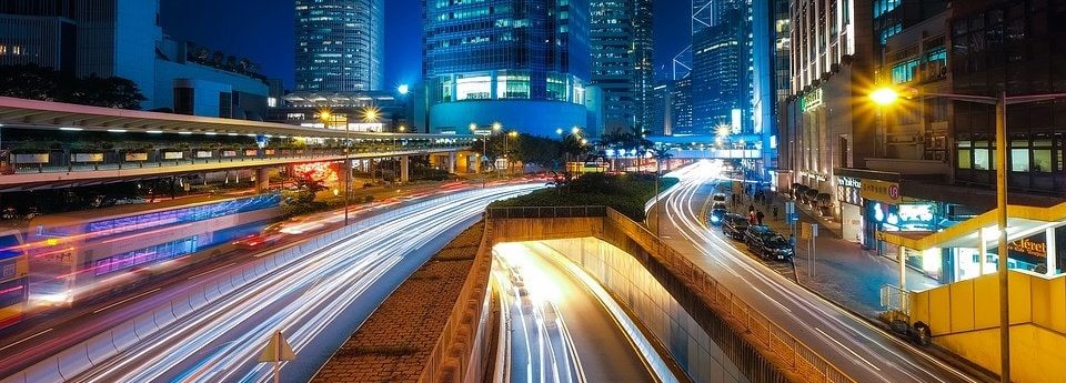 Imagen nocturna de una ciudad con rascacielos, carreteras y un tunel