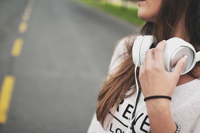 A girl holding headphones around her neck.
