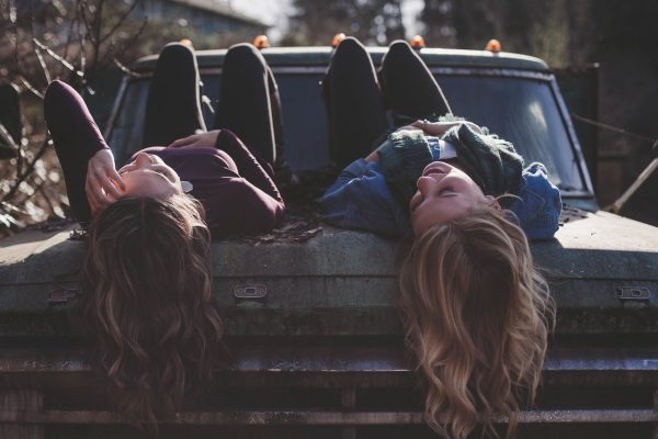 Dos chicas hablan tumbadas en un coche.